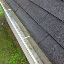White gutter cleaned along a dark shingle roof by Gutter Haven