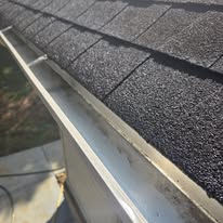 Completed light gutter along a dark shingle roof by Gutter Haven